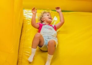 Girl having fun on yellow inflatable slide, provided by Jumptastic in Atlanta, GA